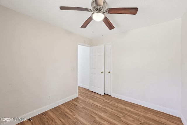 empty room with baseboards, ceiling fan, and light wood finished floors