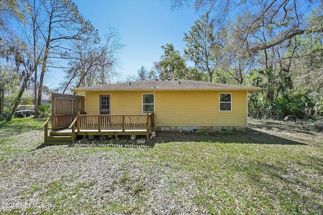 back of property featuring a deck and a lawn