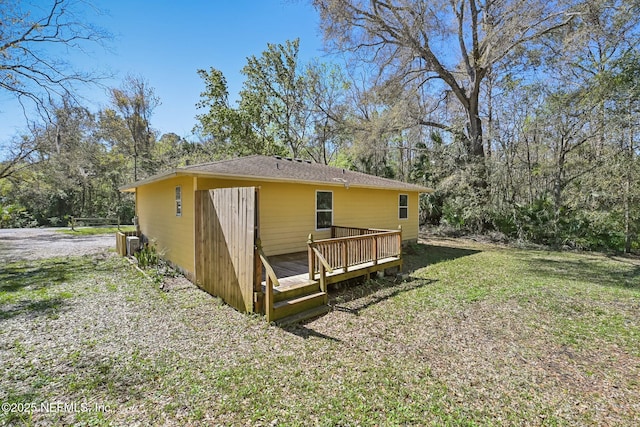 back of house featuring central air condition unit, a lawn, and a wooden deck