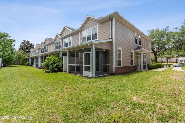 rear view of house with a lawn and a sunroom