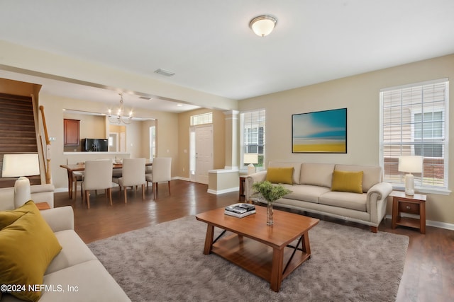 living room with dark hardwood / wood-style floors, a chandelier, a wealth of natural light, and decorative columns