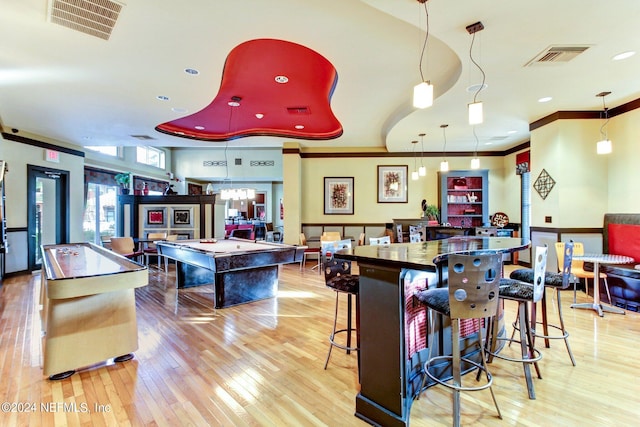 kitchen with hardwood / wood-style floors, a breakfast bar, crown molding, billiards, and decorative light fixtures