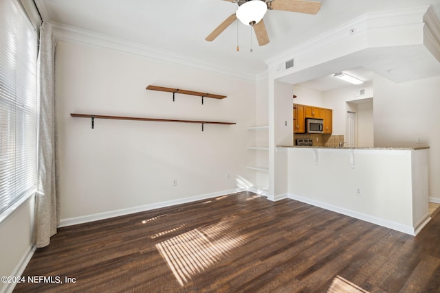 unfurnished living room with a wealth of natural light, ceiling fan, dark wood-type flooring, and ornamental molding