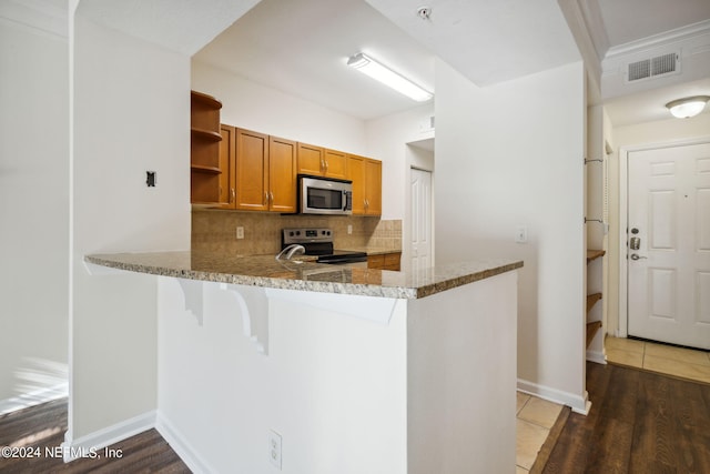 kitchen featuring backsplash, dark hardwood / wood-style floors, light stone countertops, kitchen peninsula, and stainless steel appliances