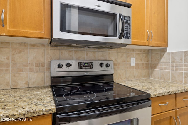 kitchen with decorative backsplash, stainless steel appliances, and light stone counters