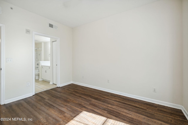 unfurnished bedroom featuring ensuite bath and wood-type flooring