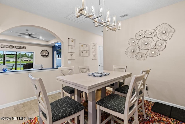 dining space featuring ceiling fan with notable chandelier