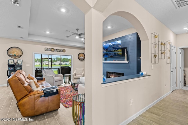 living room with ceiling fan and a fireplace