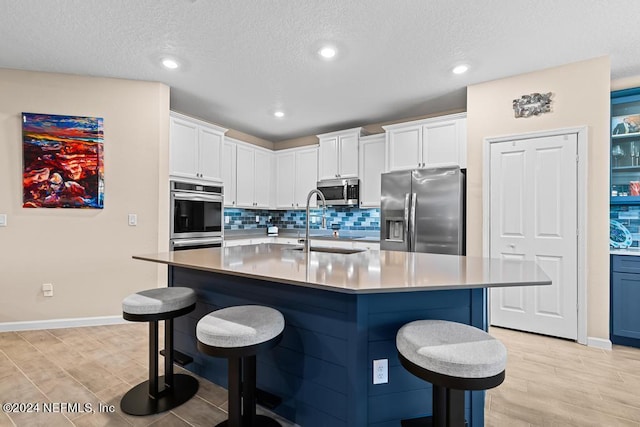 kitchen with stainless steel appliances, a center island with sink, and a breakfast bar area