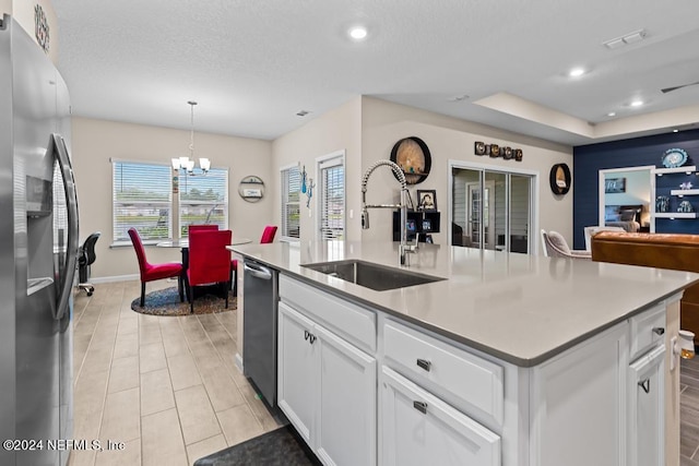 kitchen featuring appliances with stainless steel finishes, a kitchen island with sink, sink, pendant lighting, and white cabinets