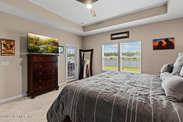 carpeted bedroom with a raised ceiling, access to exterior, and ceiling fan