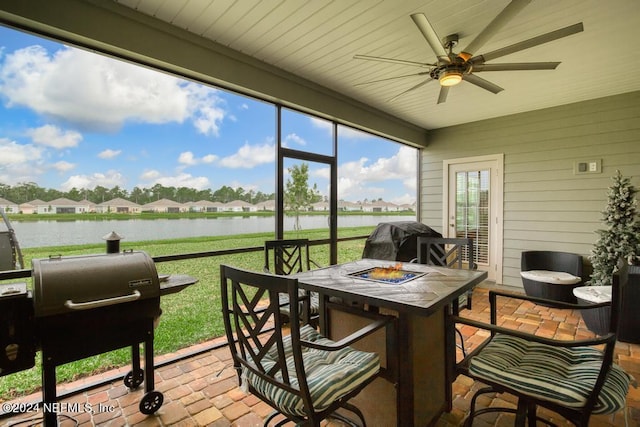 sunroom with ceiling fan and a water view