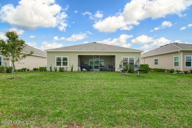 rear view of property featuring a sunroom and a lawn