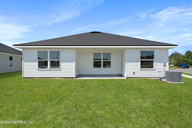 rear view of property featuring a yard, central AC unit, and a patio area