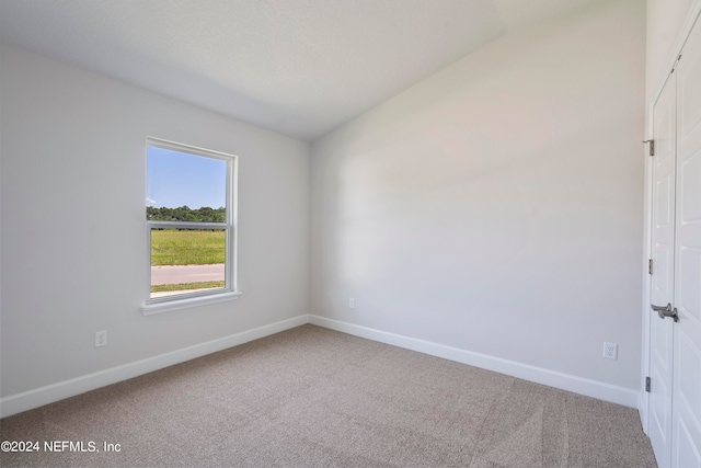 spare room featuring carpet flooring and vaulted ceiling