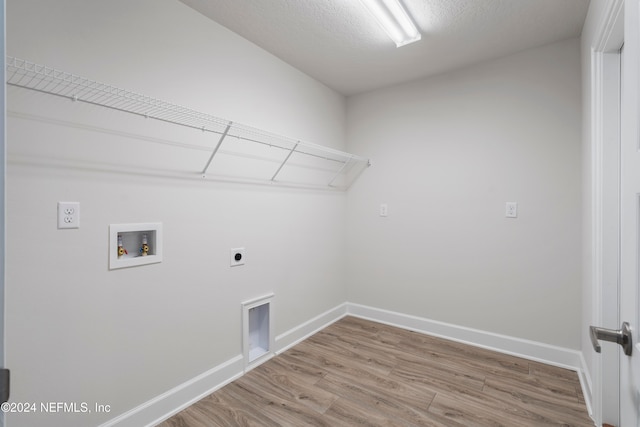 clothes washing area with hookup for an electric dryer, a textured ceiling, hookup for a washing machine, and hardwood / wood-style floors