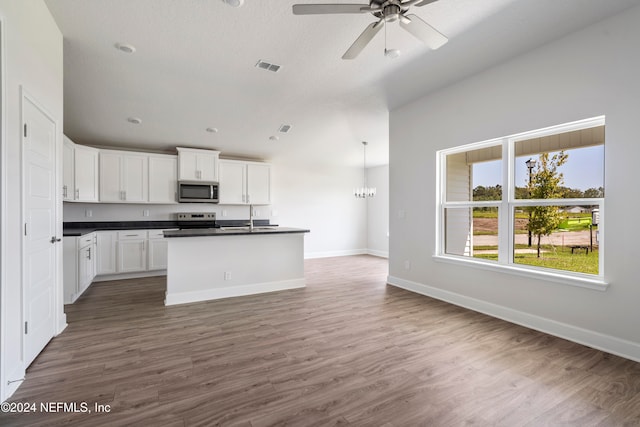 kitchen with a kitchen island with sink, dark wood-type flooring, sink, appliances with stainless steel finishes, and white cabinetry