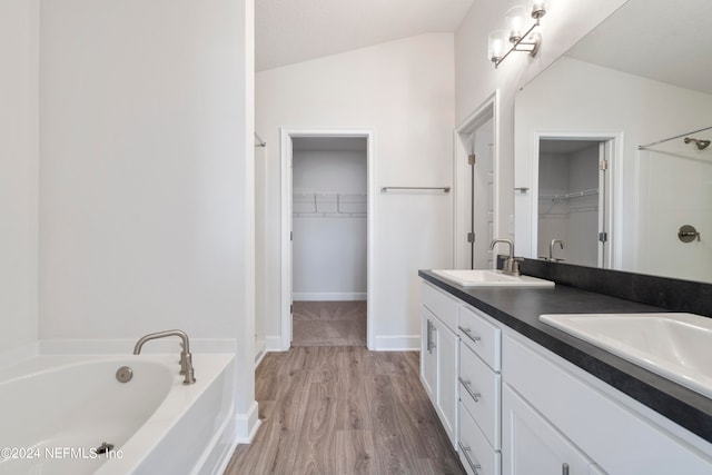 bathroom with vanity, hardwood / wood-style floors, a bathtub, and lofted ceiling