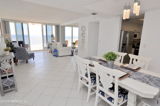 tiled dining area with floor to ceiling windows, a water view, and a notable chandelier