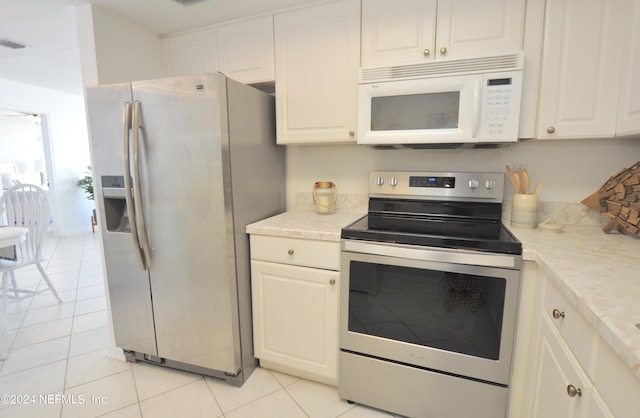 kitchen with white cabinets, light tile patterned floors, and stainless steel appliances