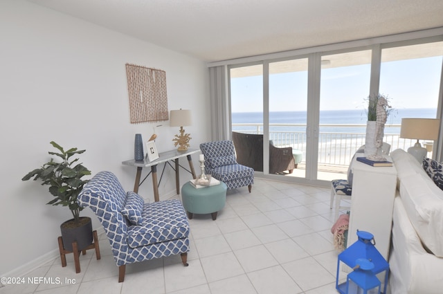 living room featuring light tile patterned floors, a water view, and a wall of windows