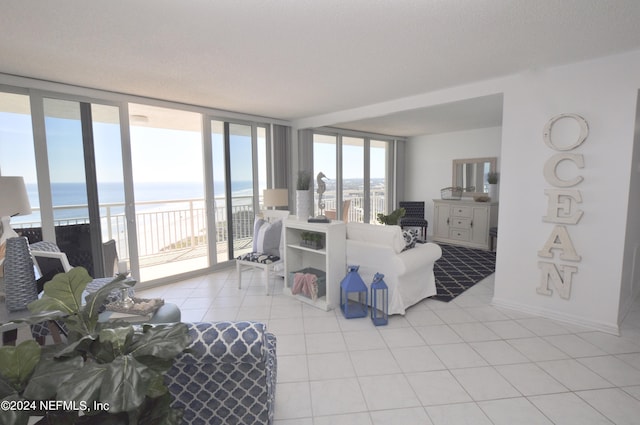 living room featuring a water view, a healthy amount of sunlight, light tile patterned floors, and a wall of windows