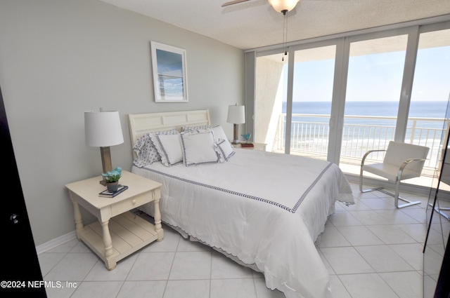 tiled bedroom featuring a water view, floor to ceiling windows, and ceiling fan