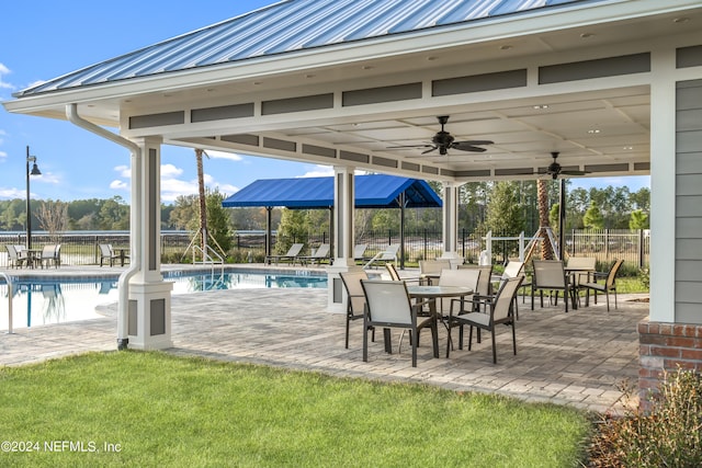 view of patio featuring a community pool, a ceiling fan, and fence