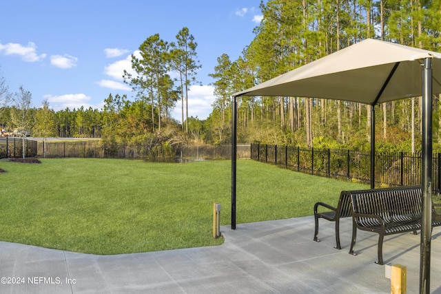 view of yard featuring a patio, a fenced backyard, and a wooded view