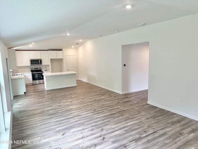 unfurnished living room with light wood-type flooring, lofted ceiling, a textured ceiling, and sink