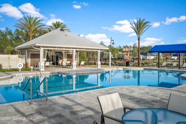 view of pool with a patio area and a playground