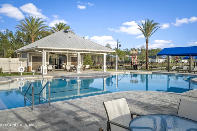 community pool featuring an exterior structure, fence, an outdoor structure, and a patio area