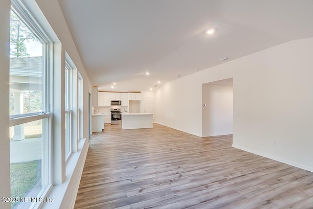 unfurnished living room featuring recessed lighting, light wood-style flooring, and vaulted ceiling