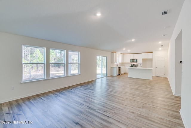 unfurnished living room with vaulted ceiling, recessed lighting, light wood-style floors, and visible vents