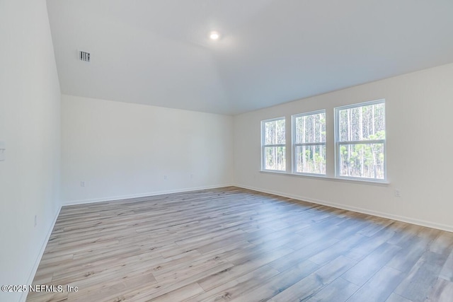 spare room with lofted ceiling, light wood-style floors, and baseboards