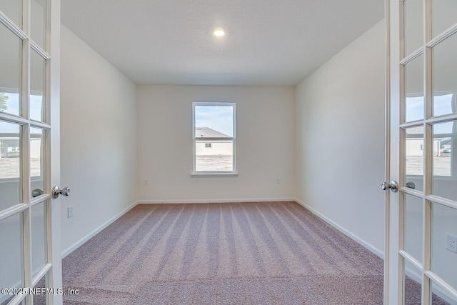 carpeted empty room with french doors and baseboards