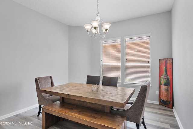 dining space with light hardwood / wood-style flooring and a notable chandelier