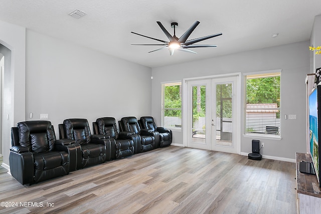 cinema room with ceiling fan, french doors, and light hardwood / wood-style floors