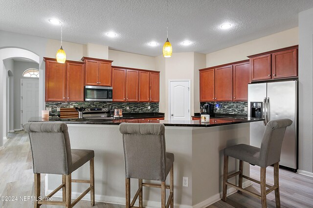 kitchen with a breakfast bar, appliances with stainless steel finishes, a textured ceiling, and pendant lighting