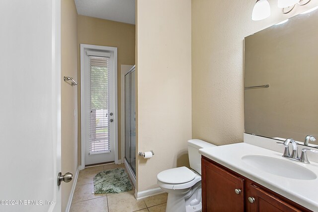 bathroom featuring toilet, vanity, tile patterned floors, and a shower with shower door