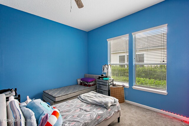 carpeted bedroom featuring ceiling fan and a textured ceiling