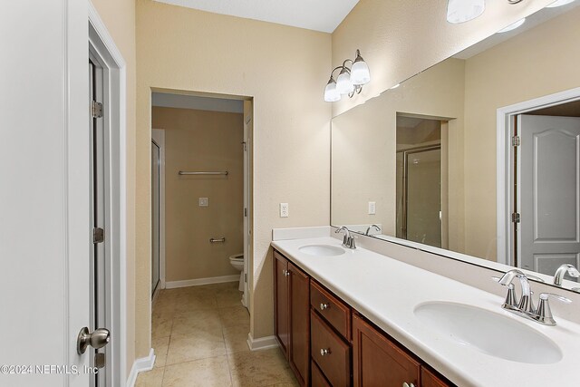 bathroom with tile patterned floors, vanity, toilet, and an enclosed shower