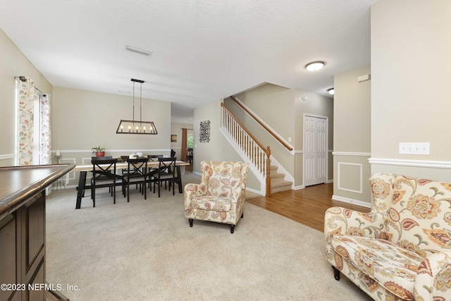 carpeted living room featuring a textured ceiling and a notable chandelier