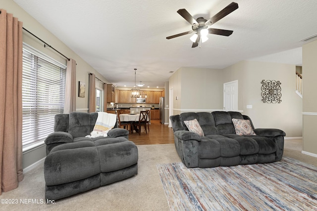 living room featuring ceiling fan with notable chandelier, plenty of natural light, and light hardwood / wood-style flooring