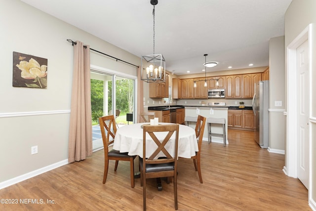 dining space featuring sink, light hardwood / wood-style flooring, and an inviting chandelier