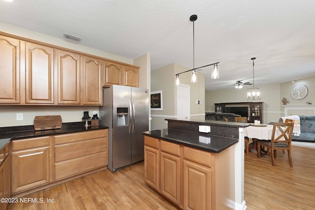 kitchen featuring light wood-type flooring, ceiling fan, pendant lighting, stainless steel refrigerator with ice dispenser, and a textured ceiling