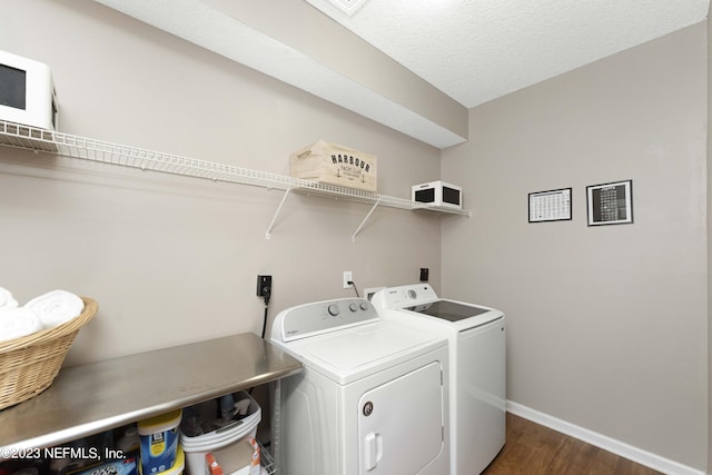 washroom with a textured ceiling, washer and clothes dryer, and dark hardwood / wood-style floors