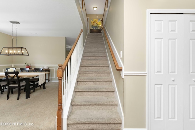 stairway with a chandelier and carpet