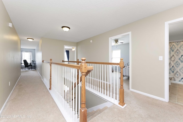 corridor with light colored carpet and a textured ceiling