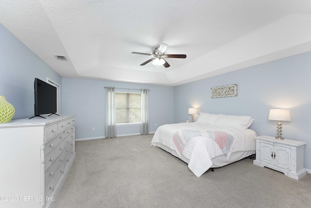 carpeted bedroom with ceiling fan, a raised ceiling, and a textured ceiling